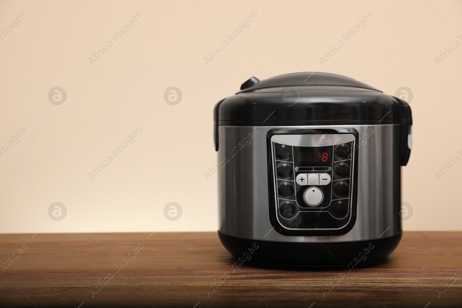 Photo of Modern electric multi cooker on table against color background. Space for text