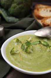 Photo of Delicious broccoli cream soup served on table, closeup. Space for text