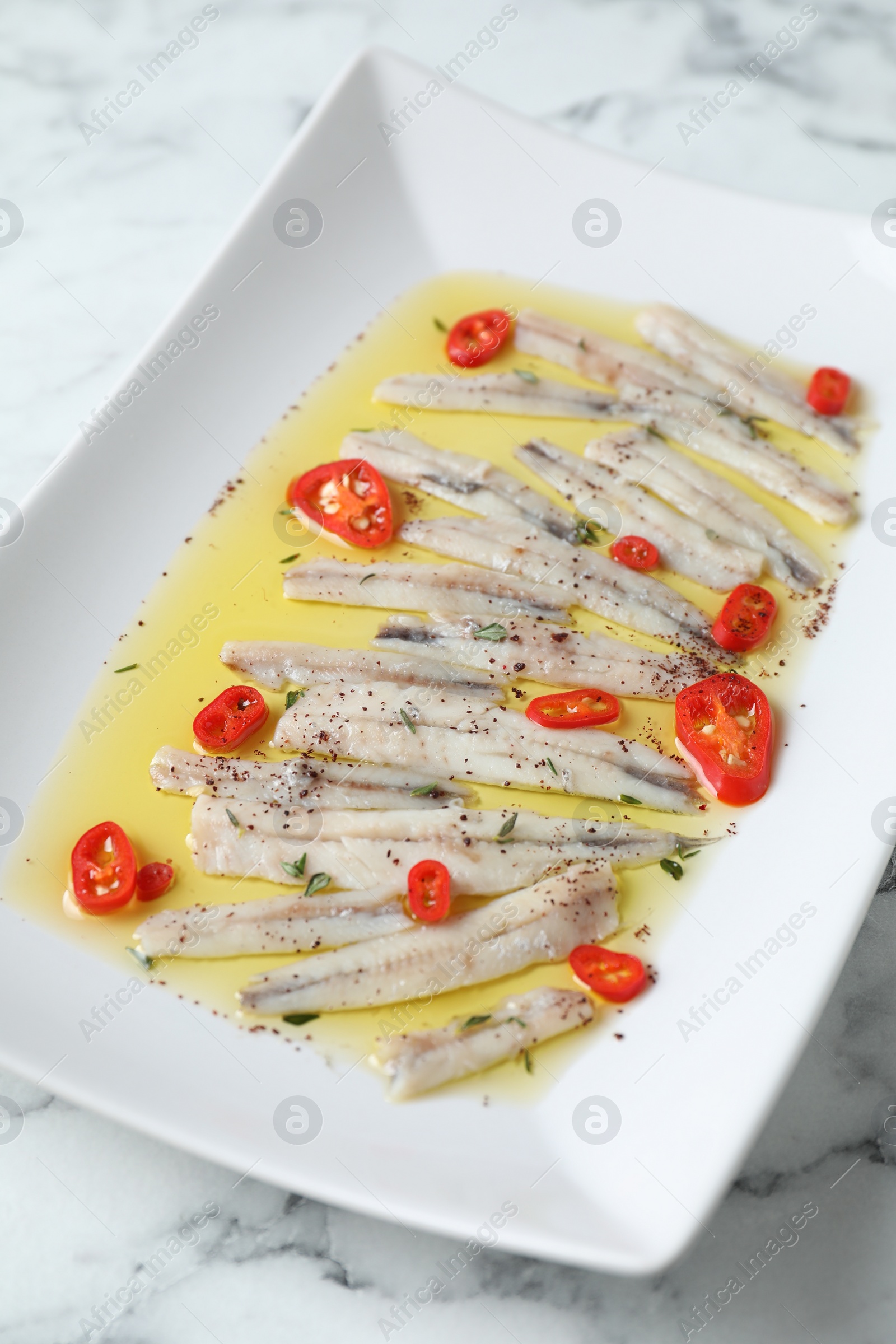 Photo of Tasty pickled anchovies with spices on table, closeup