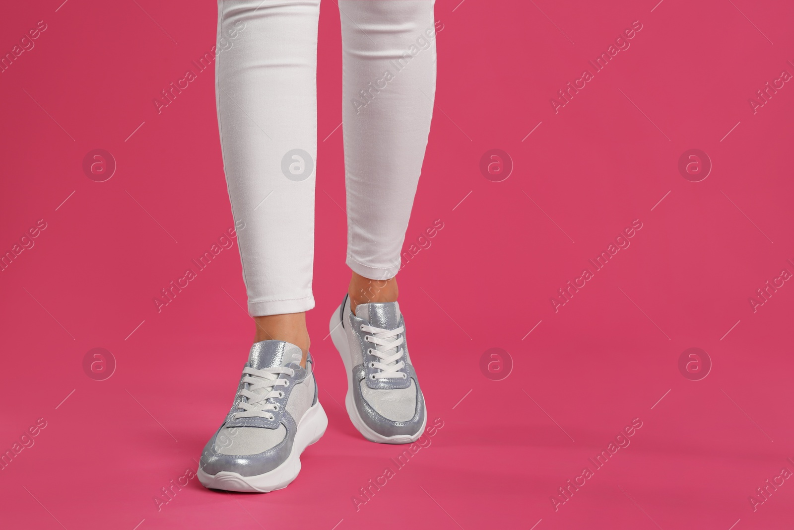 Photo of Woman wearing sneakers on pink background, closeup