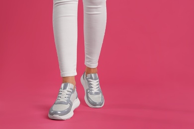 Woman wearing sneakers on pink background, closeup