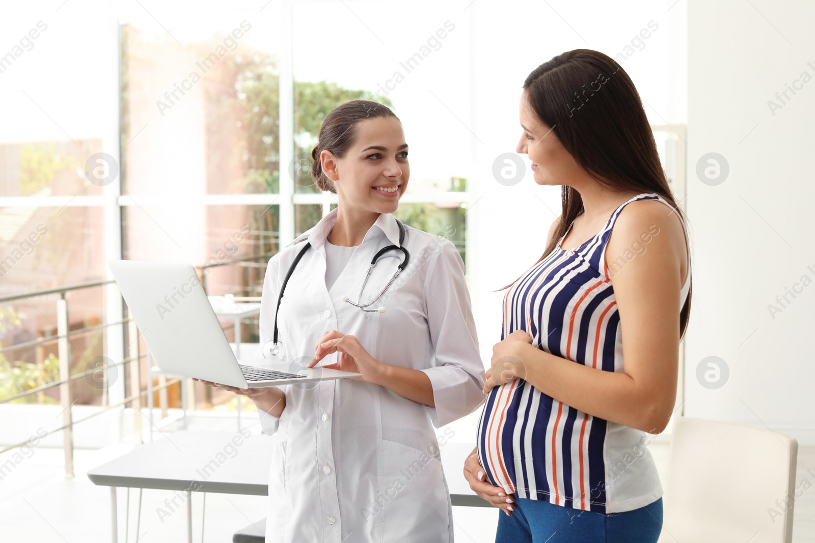 Photo of Young doctor with pregnant woman in hospital. Patient consultation