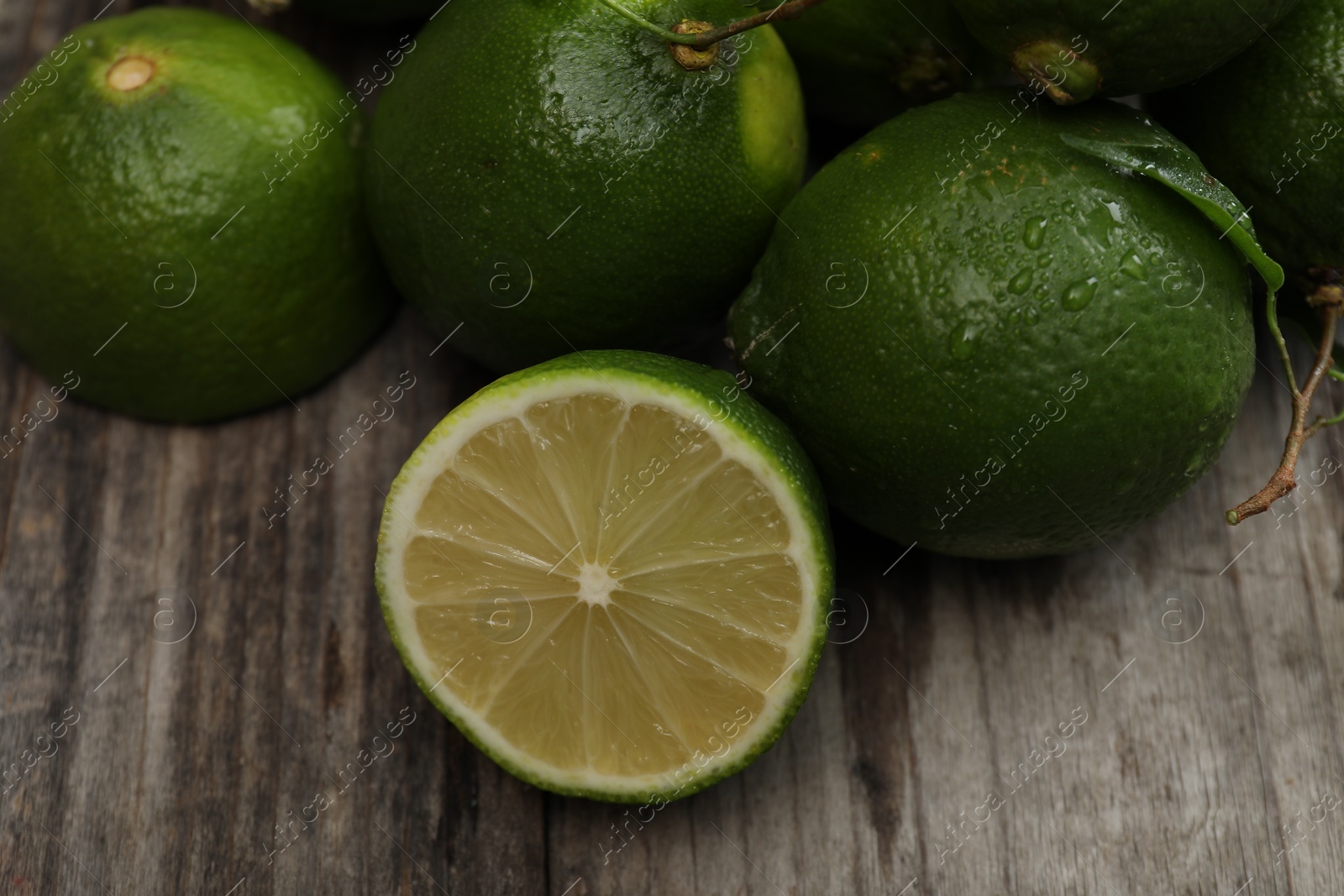 Photo of Fresh limes with water drops on wooden table, closeup