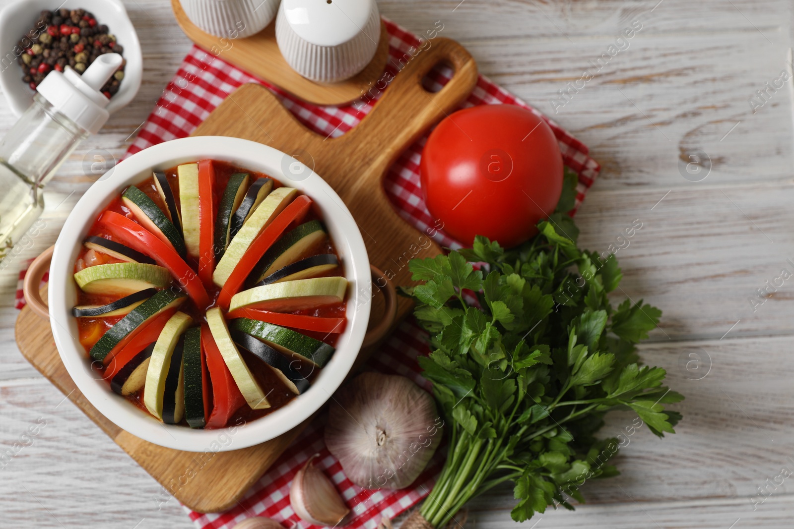 Photo of Cooking delicious ratatouille. Dish with different vegetables on white wooden table, flat lay