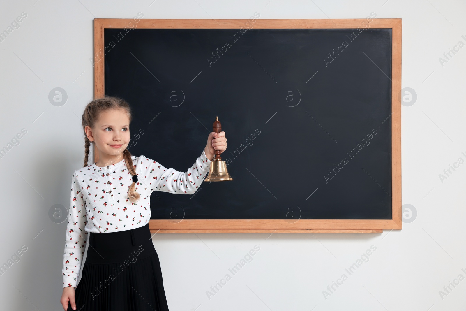 Photo of Pupil with school bell near chalkboard in classroom, space for text