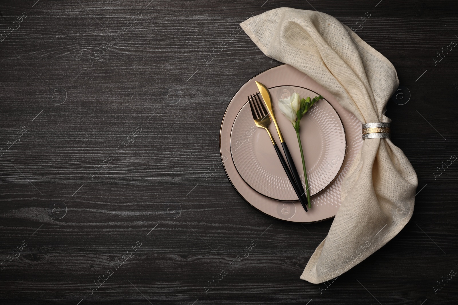 Photo of Stylish table setting. Plates, cutlery, napkin and floral decor on dark wooden background, top view with space for text