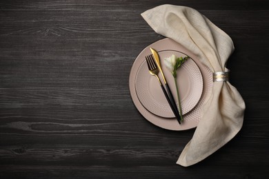 Stylish table setting. Plates, cutlery, napkin and floral decor on dark wooden background, top view with space for text