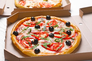Photo of Cardboard boxes with tasty pizzas on table, closeup