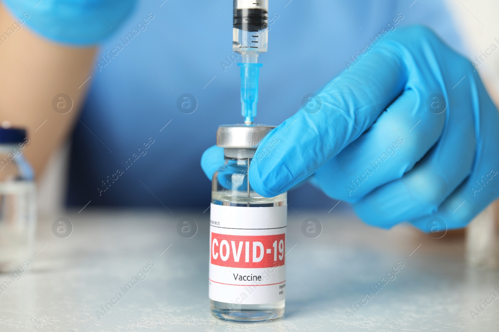 Photo of Doctor filling syringe with coronavirus vaccine at table in laboratory, closeup