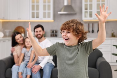 Photo of Happy family having fun at home. Son dancing while his relatives resting on sofa, selective focus