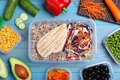 Photo of Set of plastic containers with fresh food on light blue wooden table, flat lay