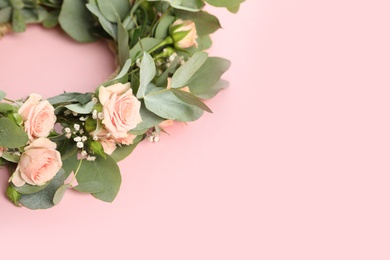 Photo of Wreath made of beautiful flowers on pink background, space for text