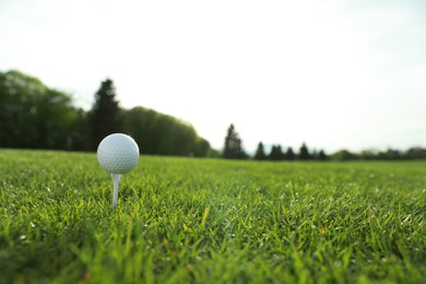 Golf ball on tee at green course, space for text