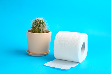 Roll of toilet paper and cactus on light blue background. Hemorrhoid problems