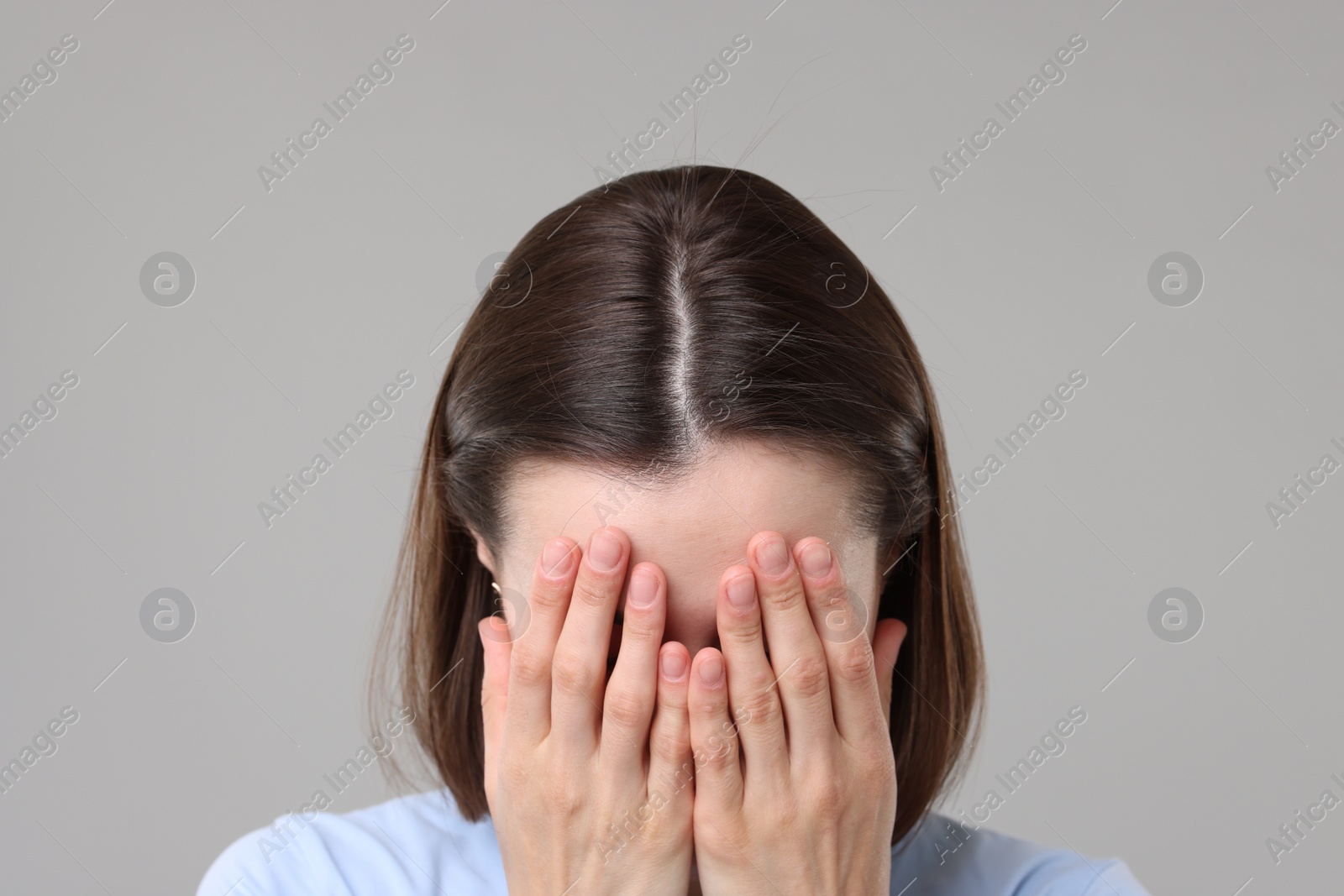 Photo of Woman suffering from hair loss problem on grey background, closeup