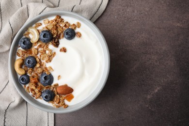 Bowl with yogurt, blueberries and granola on grey table, top view. Space for text