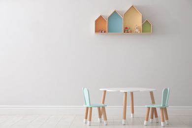 House shaped shelves and little table with chairs in children's room. Interior design