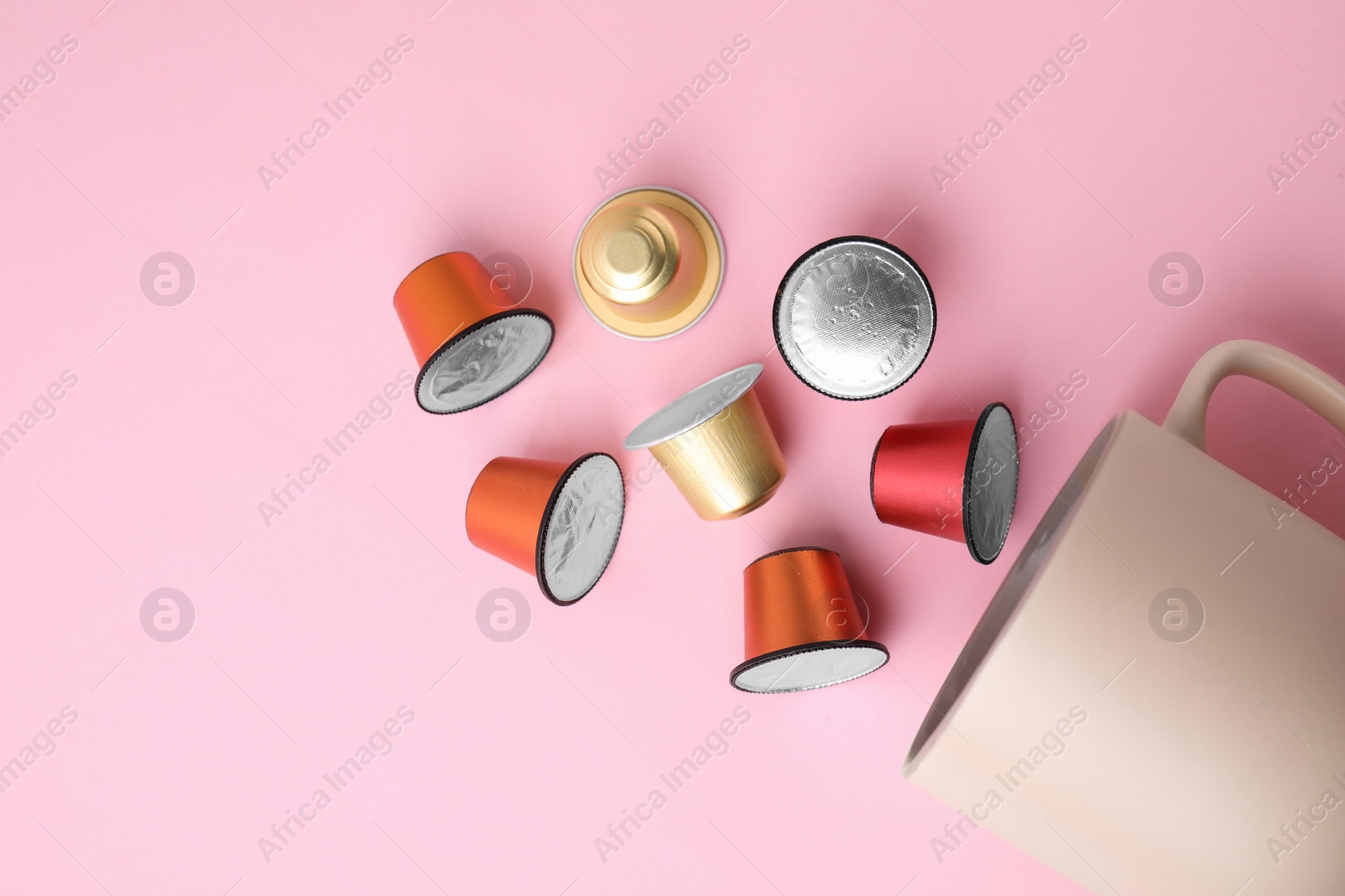 Photo of Many coffee capsules and cup on pink background, flat lay. Space for text