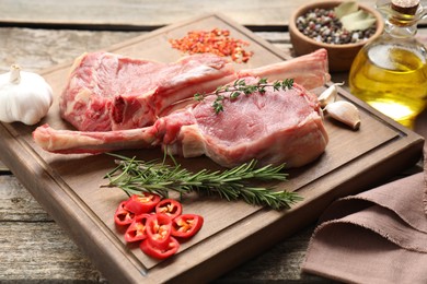 Photo of Fresh tomahawk beef cuts and spices on wooden table