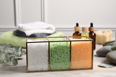 Photo of Different types of sea salt, spa products and eucalyptus branches on wooden table