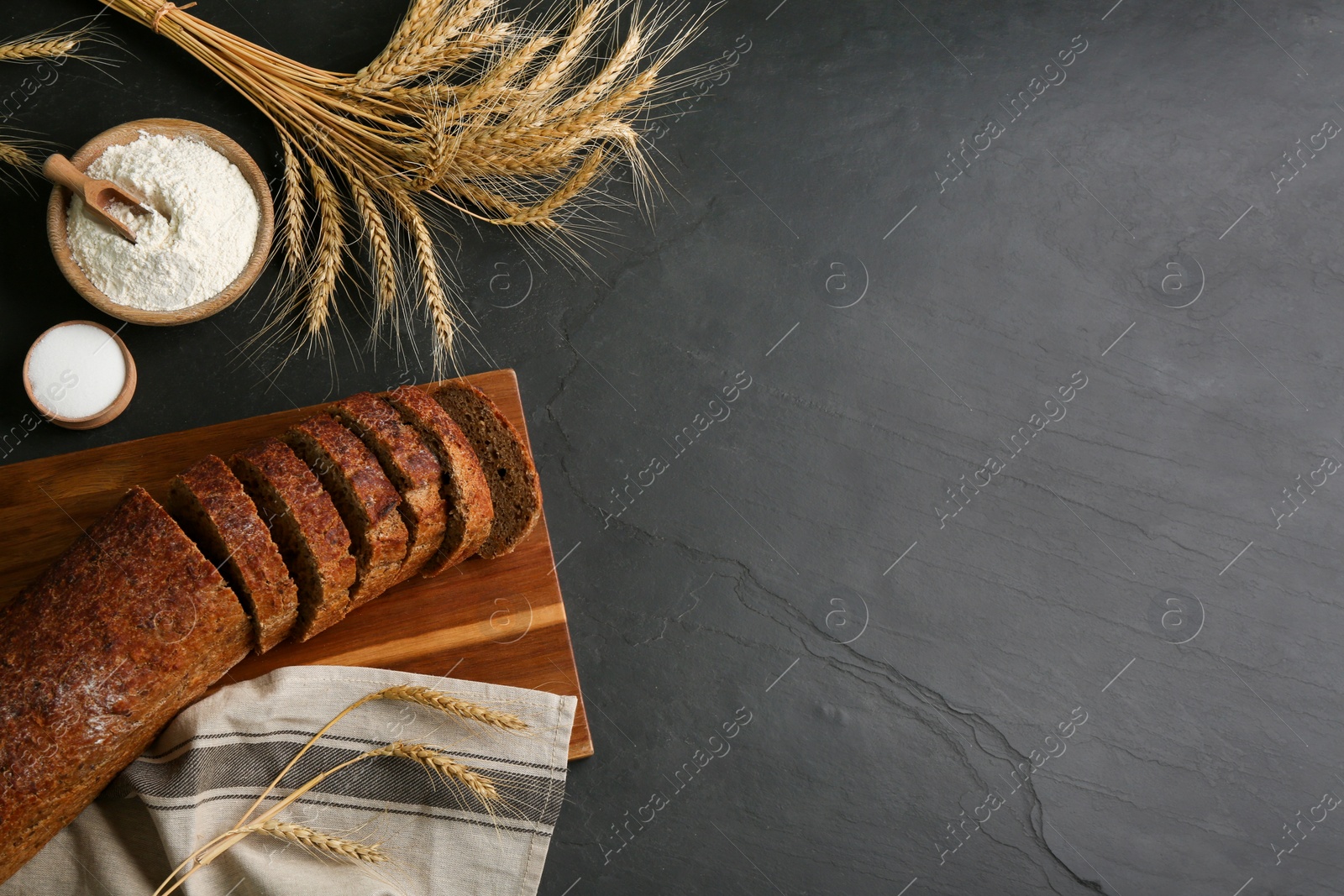 Photo of Freshly baked bread on black table, flat lay. Space for text