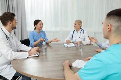 Photo of Medical conference. Teamdoctors having discussion at wooden table in clinic