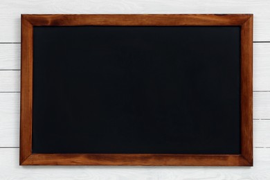 Photo of Clean black chalkboard hanging on white wooden wall