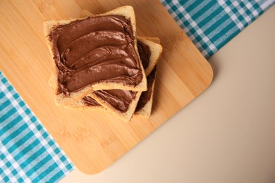 Tasty toasts with chocolate paste on beige table, top view. Space for text