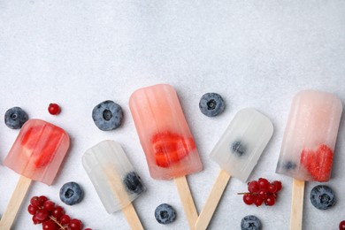 Flat lay composition with tasty berry ice pops on light table. Space for text