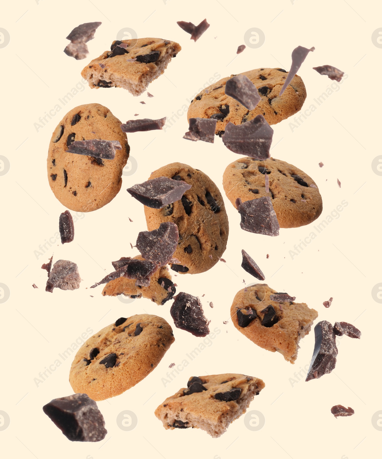 Image of Delicious chocolate chip cookies and pieces of chocolate falling on beige background