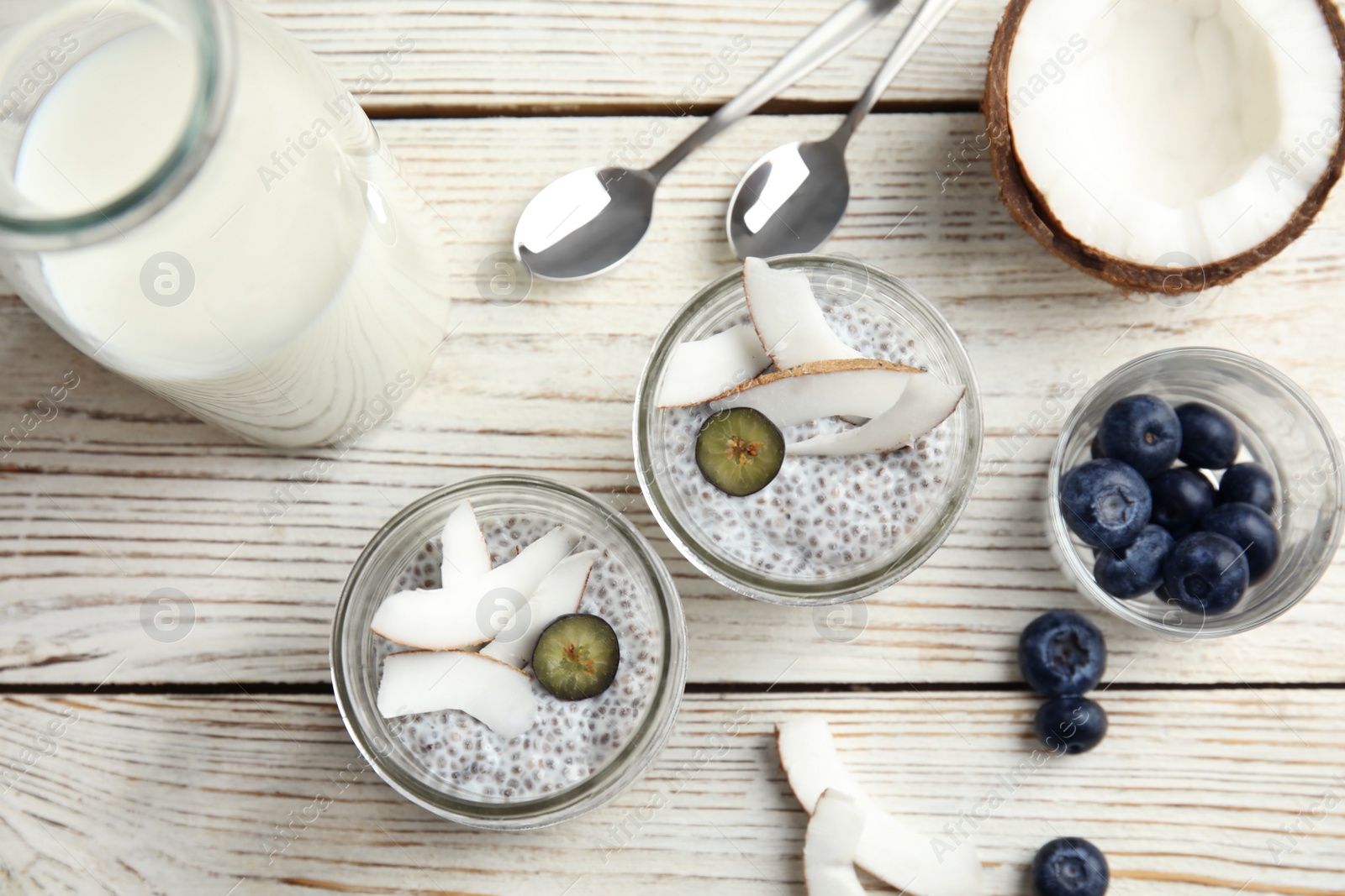 Photo of Tasty chia seed pudding with coconut in jars and ingredients on table, flat lay