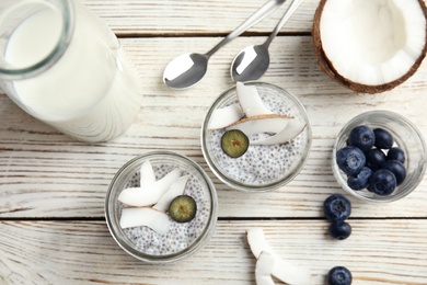 Tasty chia seed pudding with coconut in jars and ingredients on table, flat lay