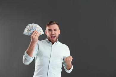 Photo of Portrait of emotional young man with money on grey background. Space for text