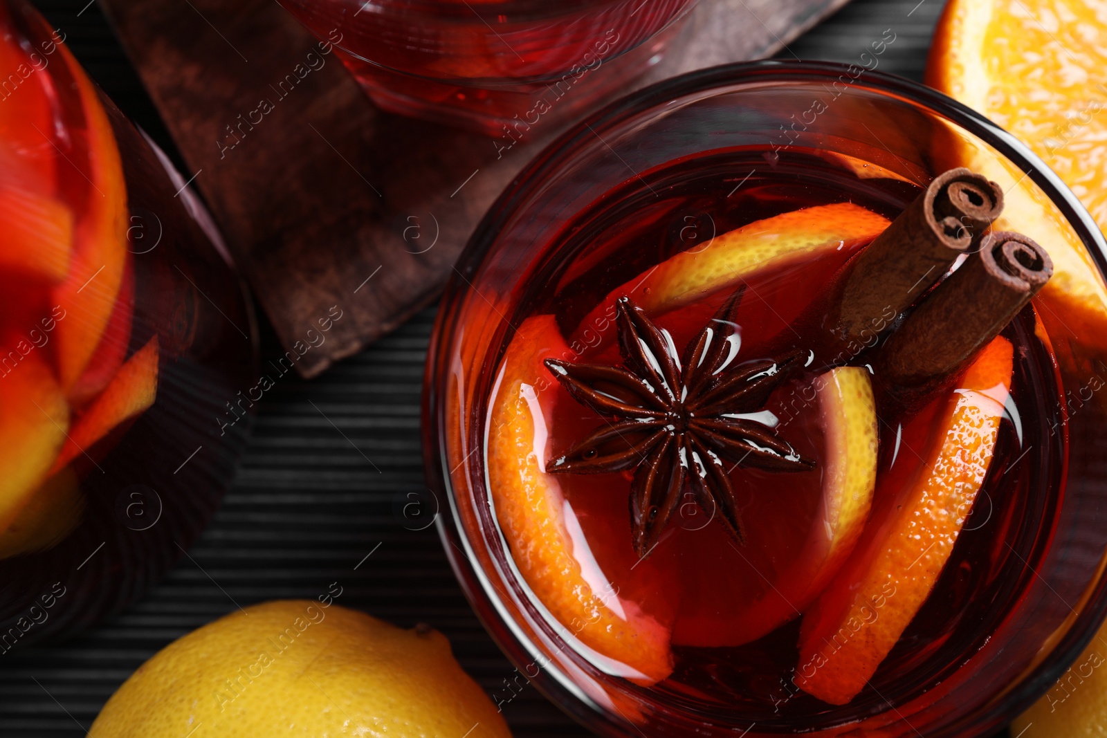 Photo of Aromatic punch drink and ingredients on black table, flat lay