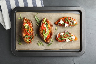 Photo of Baking sheet with stuffed sweet potatoes on grey background, top view