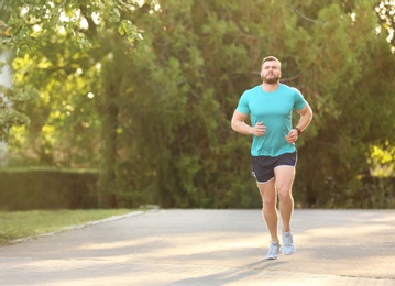 Young man running in park on sunny day