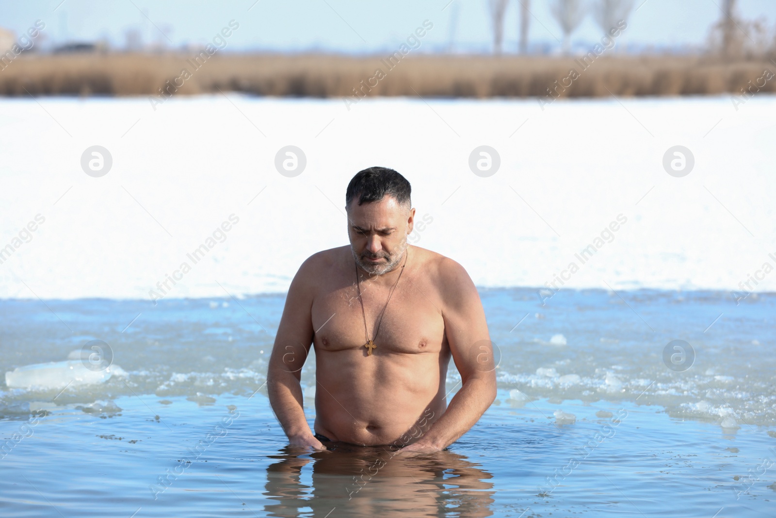 Photo of MYKOLAIV, UKRAINE - JANUARY 19, 2021: Man immersing in icy water on winter day. Traditional Baptism ritual