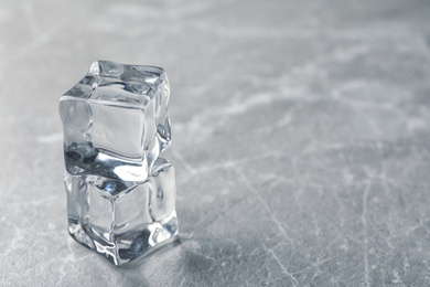 Photo of Crystal clear ice cubes on grey table. Space for text