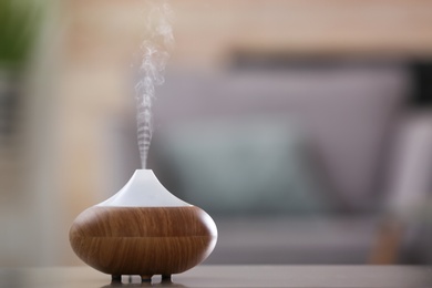 Aroma oil diffuser lamp on table against blurred background