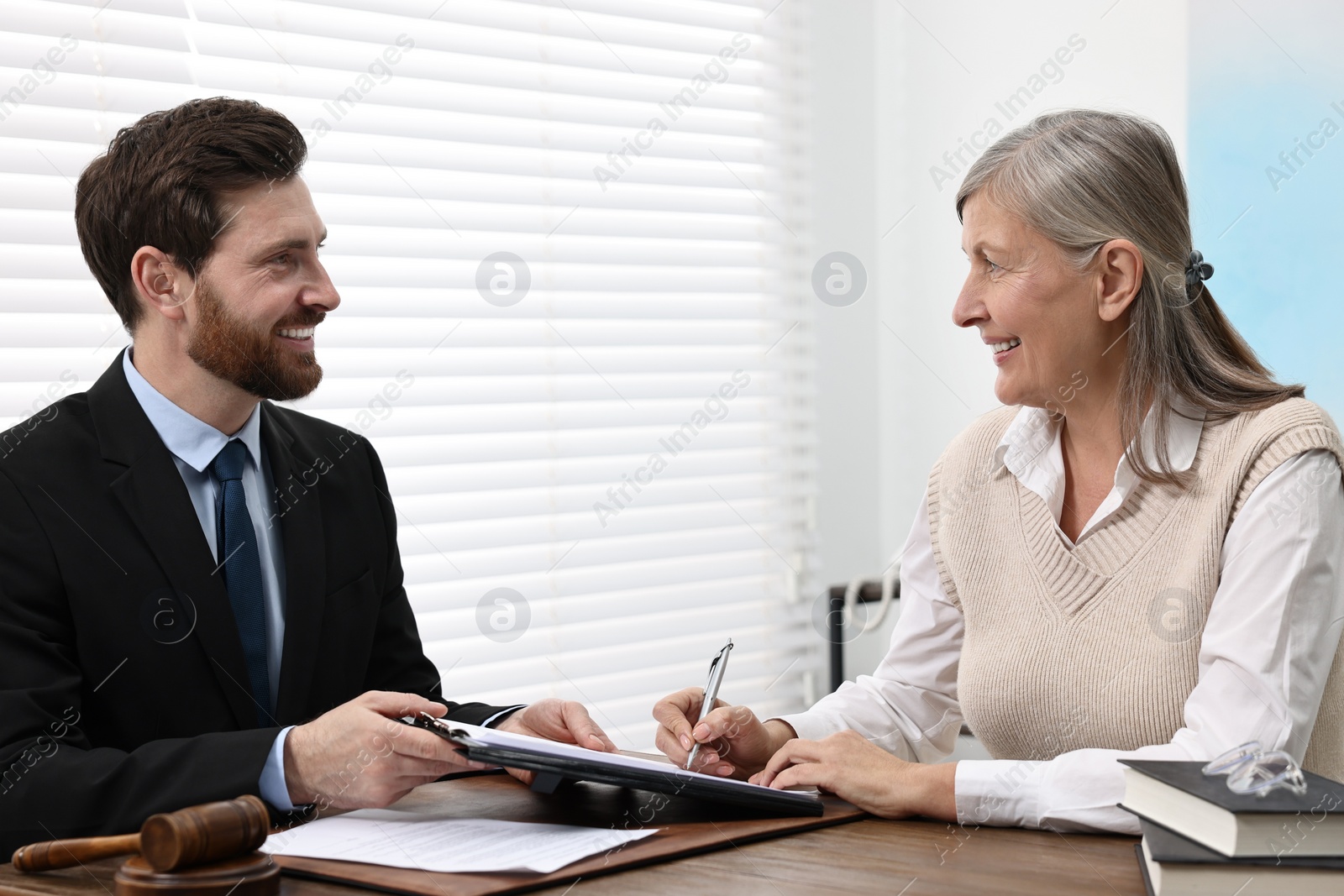 Photo of Senior woman signing document in lawyer's office