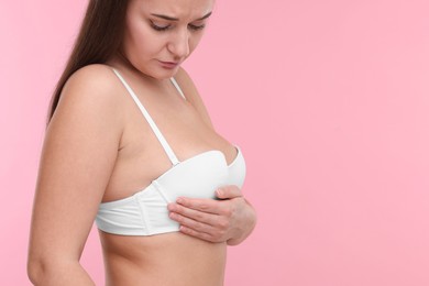 Mammology. Woman in bra doing breast self-examination on pink background, space for text