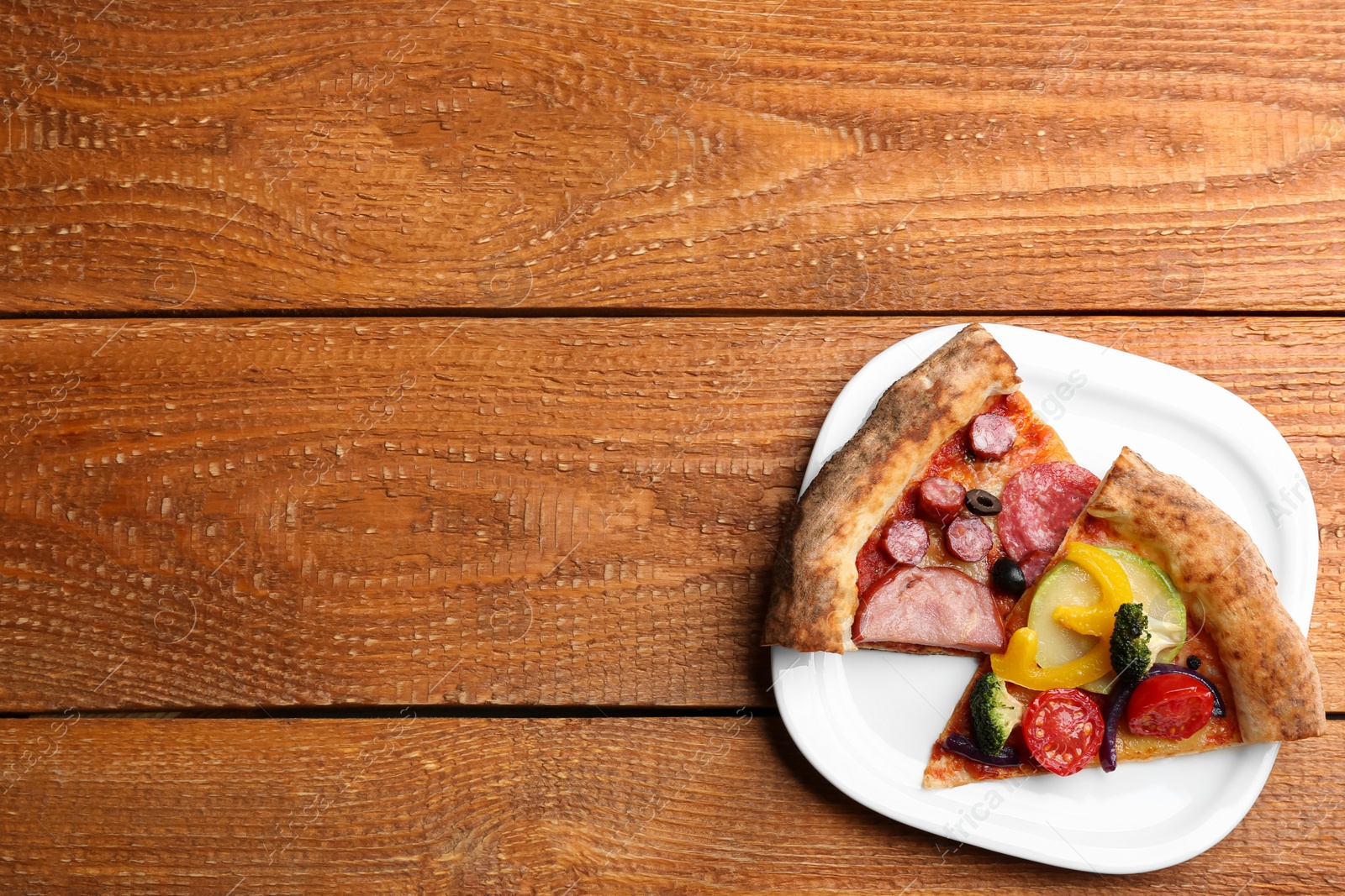 Photo of Slices of different delicious pizzas on wooden table, top view. Space for text