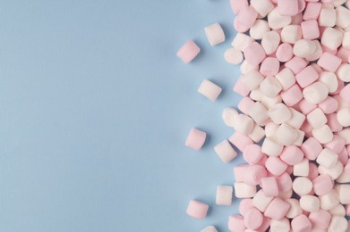 Delicious marshmallows on light blue background, flat lay. Space for text