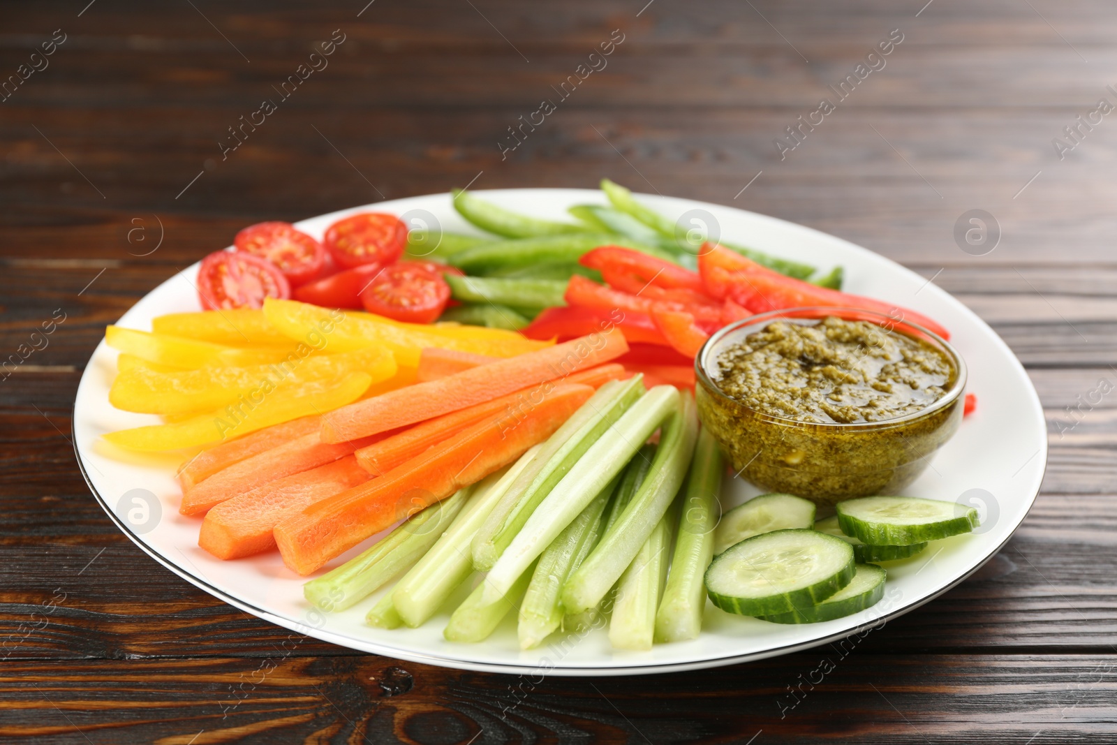 Photo of Celery and other vegetable sticks with dip sauce on wooden table