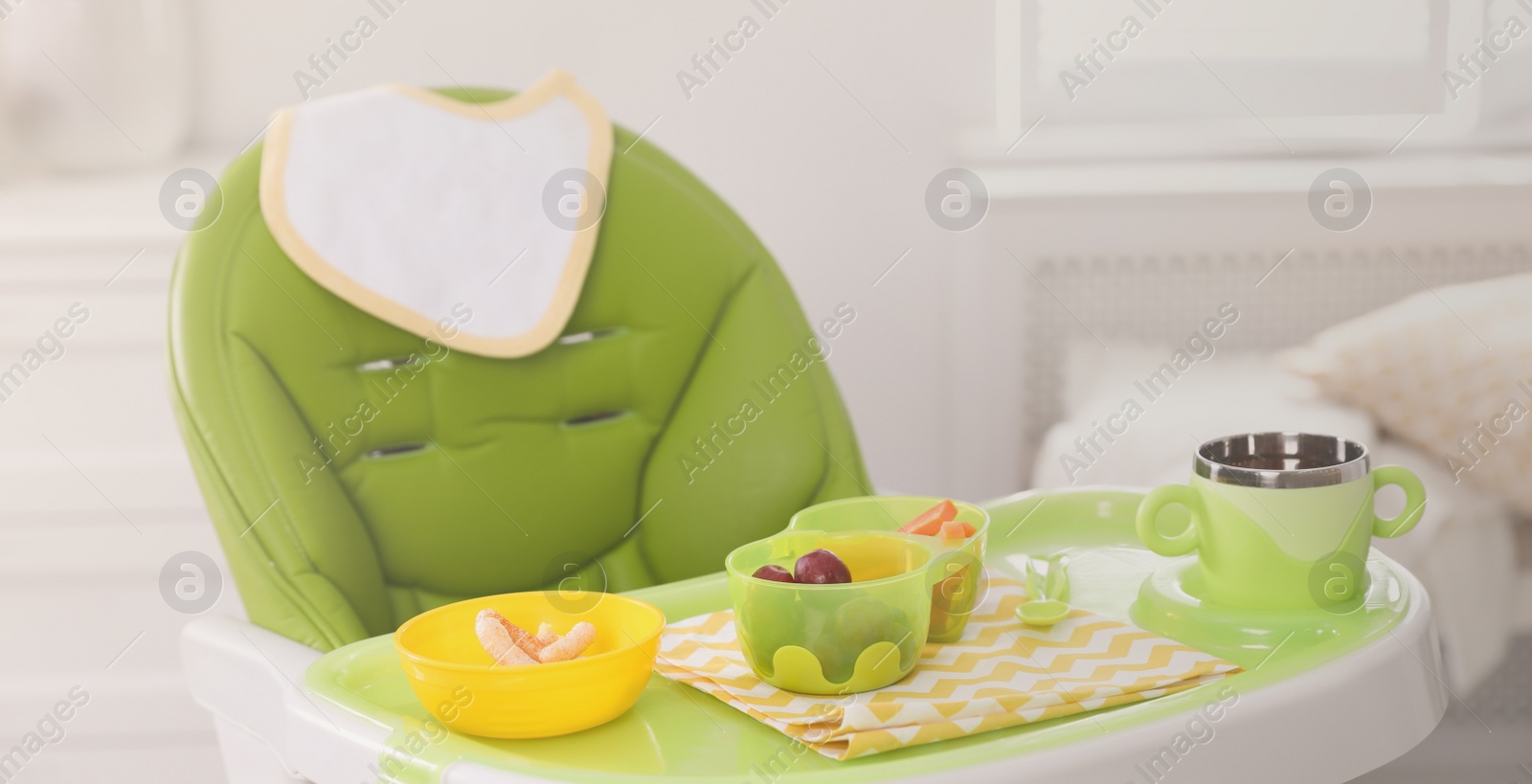 Image of High chair with food in baby tableware on tray indoors. Banner design