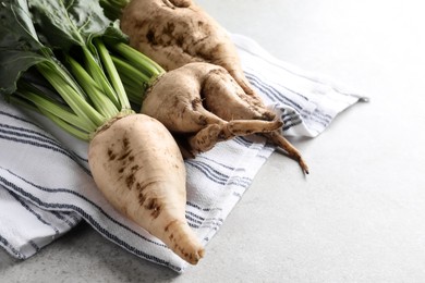 Fresh sugar beets with leaves on light grey table, closeup