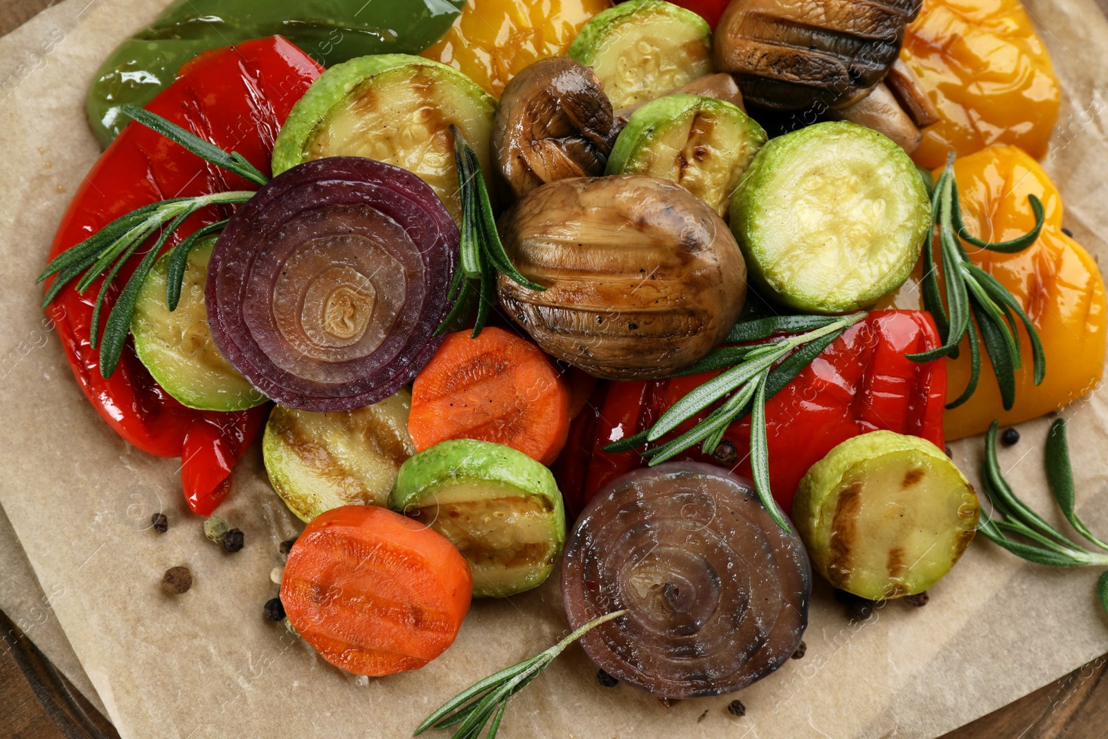 Photo of Delicious grilled vegetables with rosemary on parchment, closeup