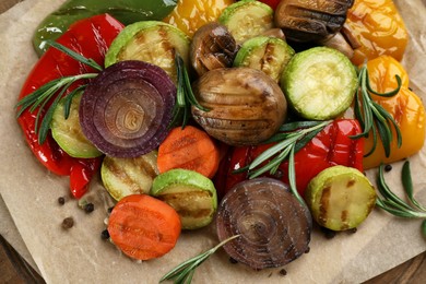 Photo of Delicious grilled vegetables with rosemary on parchment, closeup