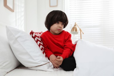 Photo of Sad little boy finding tree twig under pillow in bed at home. Saint Nicholas day tradition