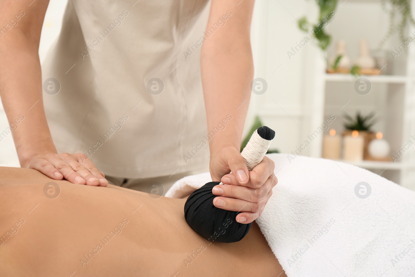 Photo of Young woman receiving herbal bag massage in spa salon, closeup